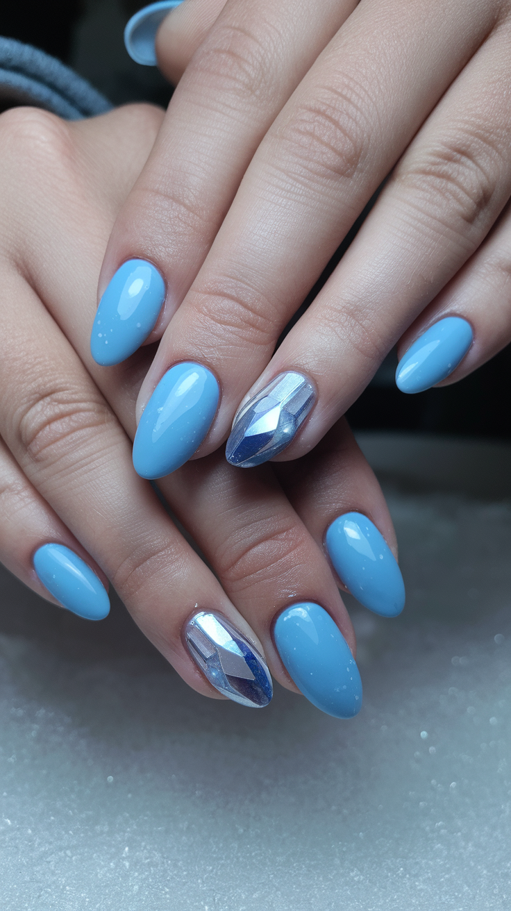 Close-up of hands with light blue nail polish featuring a gem-like accent nail, representing ice crystal nails.