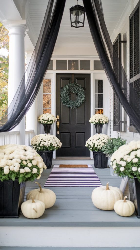 black planters, white pumpkins, black wreath on door, black gauze fabric framing the entrance